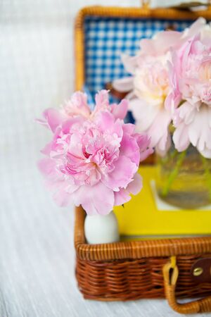 A very beautiful bouquet of pink peonies stands in a vase on a wooden suitcase. Beautiful composition.の写真素材