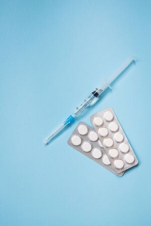 On a blue background are pills and syringe. Health and self-control concept for viruses and epidemics. Close-up. View from above.の写真素材