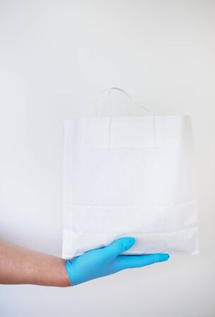 Home delivery service, a guy in gloves delivers a bag of food to the door. Contactless delivery during a pandemic virus. Close-up.の写真素材