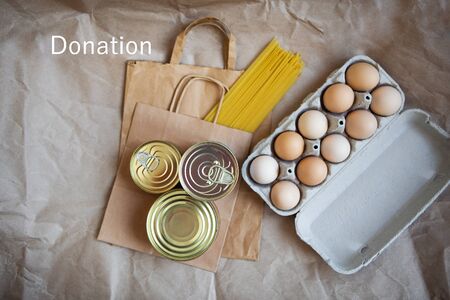 Eggs, canned food, pasta, products in environmentally friendly craft packages. Vegetarian healthy organic foods from the market. Donation, help for those in need. Lettering donation.の写真素材