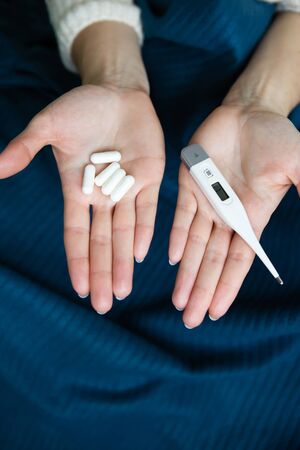 Girl holds pills in her right hand and a thermometer in her left. Arms outstretched before you. The concept of self-control and self-control in viruses and epidemics.の写真素材