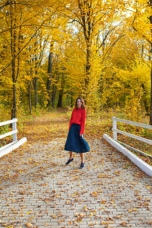Beautiful girl in a red sweater near a white wooden fence. Beautiful autumn.の写真素材