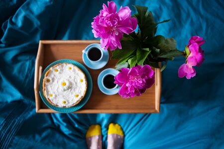 Coffee, pink peonies, cheesecake on a wooden tray, top viewの写真素材