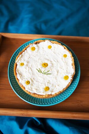 A cream cheesecake stands on a wooden tray in bed. View from aboveの写真素材