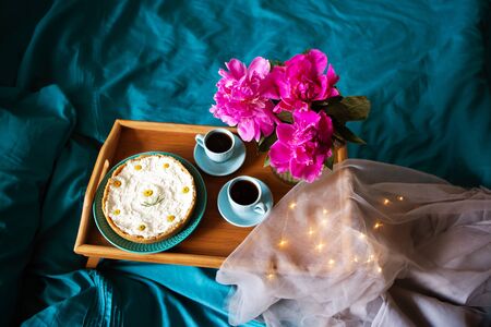 Beautiful morning Vanilla cheesecake, coffee, blue cups, pink peonies in a glass vaseの写真素材