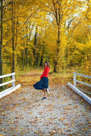 Beautiful girl in a red sweater near a white wooden fence. Beautiful autumn.の写真素材