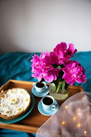 Beautiful morning Vanilla cheesecake, coffee, blue cups, pink peonies in a glass vaseの写真素材