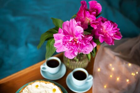 Beautiful morning Vanilla cheesecake, coffee, blue cups, pink peonies in a glass vaseの写真素材
