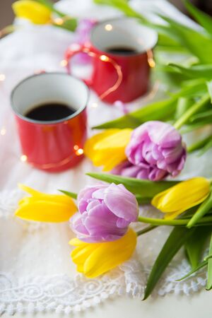 Beautiful morning, two cups of coffee and a bouquet of bright and beautiful tulips. Close-upの写真素材
