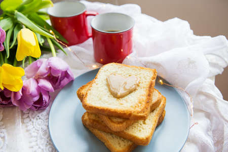 Homemade breakfast in bed. Toast with peanut butter, a cup of coffee and tulips. Good morningの写真素材