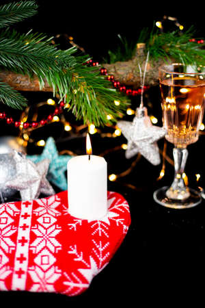 New Year holiday concept. New Year's decor - champagne glasses, New Year's toys, a Christmas tree with decorations, a candle is lit for making a wishの写真素材