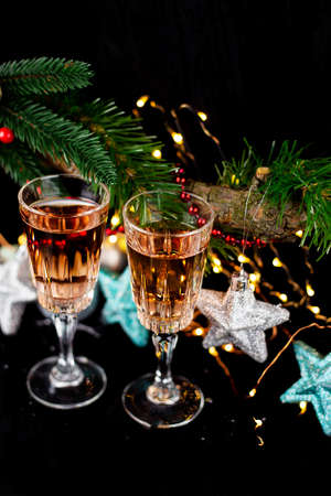New Year and Christmas decor. Glasses for champagne, toys for the Christmas tree stand on the table in front in the dark, beautiful bokeh on the background. Close-up, top viewの写真素材