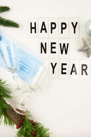Medical mask, champagne glasses, New Year decorations. Happy new year lettering, top viewの写真素材