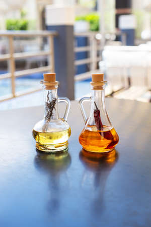On the table are two glass bottles filled with spicy and rosemary olive oil. Close-up. Butter for pizza, rest in an Italian restaurantの写真素材