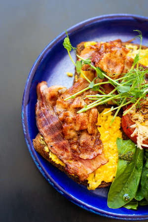 Very bright and healthy breakfast on a plate - bacon, egg, salad, tomato, cheese, a glass of yogurt. Close-up, top viewの写真素材