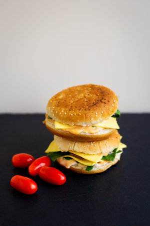 Tasty hamburger with tomatoes, cutlet, watercress and onions on a black slate, on the side are cherry tomatoes. Space for textの写真素材