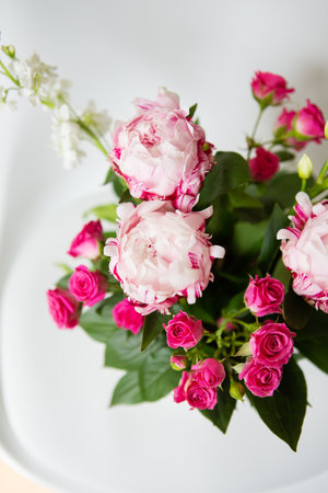 A beautiful bouquet of tender pink peonies and small roses stands on a white chair. Suitable for bridal bouquet, birthday. Close-up, top viewの写真素材