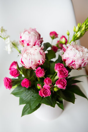 A beautiful bouquet of tender pink peonies and small roses stands on a white chair. Suitable for bridal bouquet, birthday. Close-up, top viewの写真素材