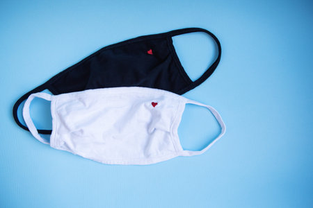 Protective mask with embroidery in the form of a heart on a blue background. The concept of quarantine and isolation during a coronavirus pandemic. Close-up. Place for an inscription ..の写真素材