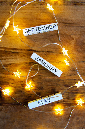 Perpetual calendar on a wooden table, different months against the background of garlands in the starsの写真素材