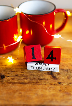 Two cups of coffee in red cups on a background of garlands. Postcard with date and month. Morning surprise for Valentine's Day. View from aboveの写真素材