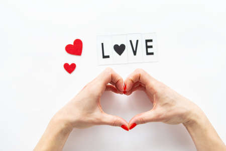 Female hands in the shape of a heart isolated on a white background, side view of small red hearts. Love letteringの写真素材