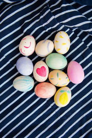 Beautiful Easter eggs painted with watercolors lie on a striped blue fabricの写真素材