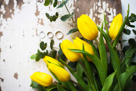 Beautiful wedding rings with yellow tulips on old white tableの写真素材