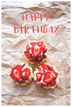 Beautiful and bright cupcakes with strawberries, the inscription of a happy birthday.の写真素材