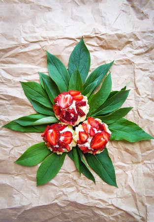 Beautiful and bright cupcakes with strawberries lie on green leaves.の写真素材