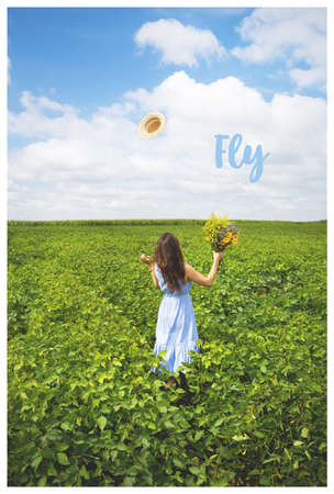 the girl is standing in the field with a bouquet of yellow flowers and a straw hat.の写真素材