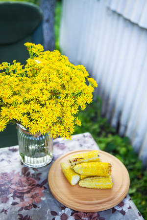 Delicious, sweet young grilled popcorn lies on a wooden board, outdoor recreation, proper nutrition. Close-upの写真素材
