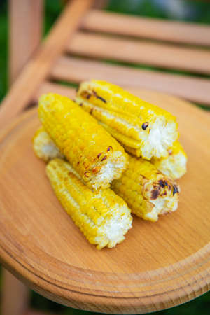 Delicious, sweet young grilled popcorn lies on a wooden board, outdoor recreation, proper nutrition. Close-upの写真素材