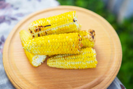 Delicious, sweet young grilled popcorn lies on a wooden board, outdoor recreation, proper nutrition. Close-upの写真素材