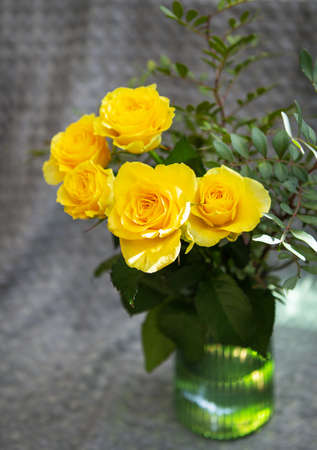 Beautiful yellow roses in a green vase stand on a blanket. Surprise and holiday conceptの写真素材