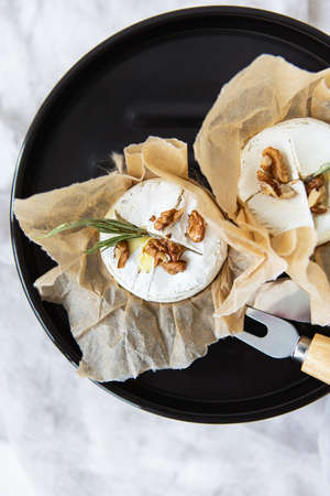 Baked camembert with walnuts and honey wrapped in parchment lies on a grill stand, delicious and healthy foodの写真素材