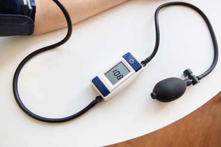 Health and care concept. Measurement of blood pressure. The woman measures blood pressure. Self-diagnosis at home. View from aboveの写真素材