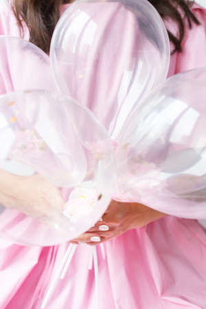 Happy woman holds in her hands a lot of air pink balloons with candy. Holiday and surprise conceptの写真素材