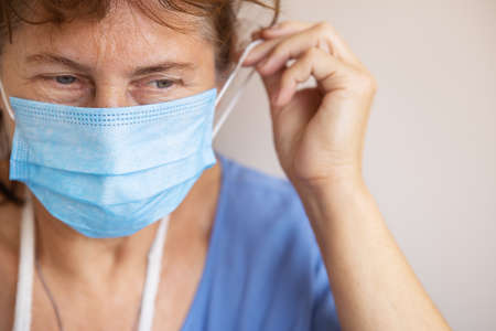 Doctor or nurse taking off her medical mask, portrait, close up, white background, copy spaceの写真素材