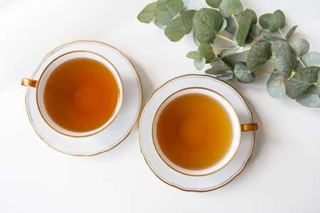Two cups of black tea in a porcelain beautiful white cup with a gold cut. Beautiful bouquet of purple hydrangea on the table. Tea breakの写真素材