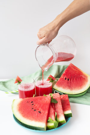 A glass of freshly squeezed fresh watermelon juice, a healthy watermelon and mint leaf smoothie is on a green napkinの写真素材