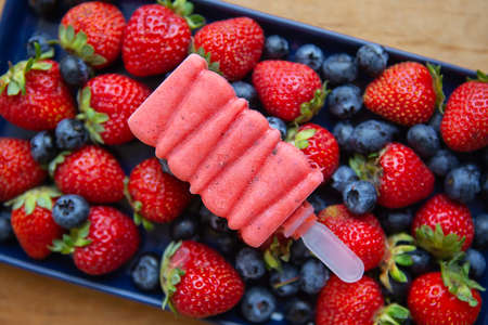 Delicious ice cream from fresh strawberries and blueberries close-up lies on fresh strawberries and blueberries. Assorted backgroundの写真素材
