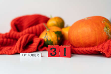 Wooden cube calendar showing Halloween October 31st, with pumpkins in the background. Holiday and party conceptの写真素材