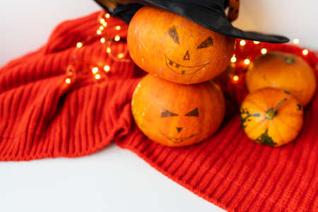 Two pumpkins with a painted face on a red sweater. Holiday concept of October 31, Halloween....