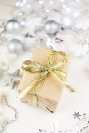 In the center of the assorted Christmas toys, there is a golden gift box created from kraft paper on a white backgroundの写真素材