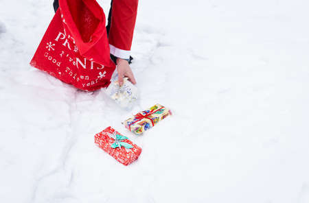 A man dressed as Santa Claus collects gifts in a snowy forest in the snow, colorful boxes with giftsの写真素材