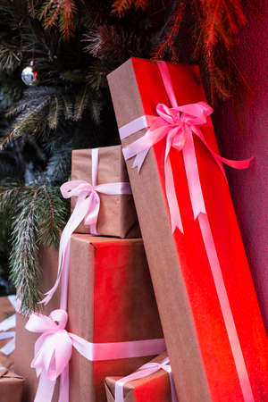 Craft gift boxes on the street near a wall made of a Christmas tree and fir. red neon shines on boxes.Christmas and new year concept. December 25の写真素材
