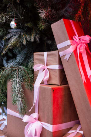 Craft gift boxes on the street near a wall made of a Christmas tree and fir. red neon shines on boxes.Christmas and new year concept. December 25の写真素材