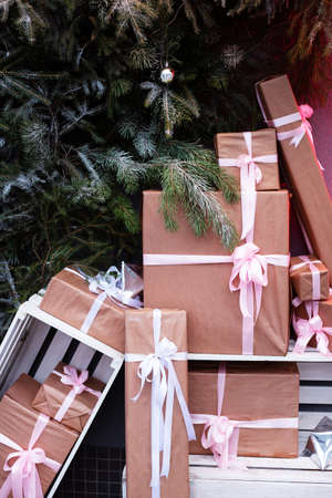 Craft gift boxes on the street near a wall made of a Christmas tree and fir. Christmas and New Year...