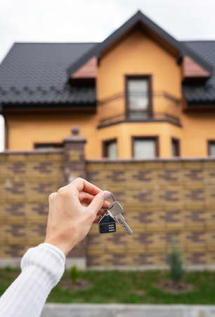 A young adult woman holds a curl with a curl from her new home in her hands. Mortgage, home purchase, long-term lease agreementの写真素材